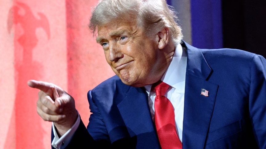 President Donald Trump points his finger and smiles at an audience.